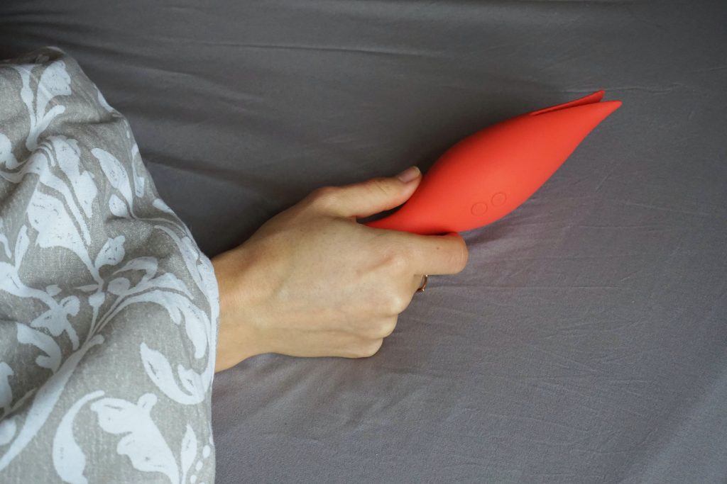 woman holding a red clitoral vibrator